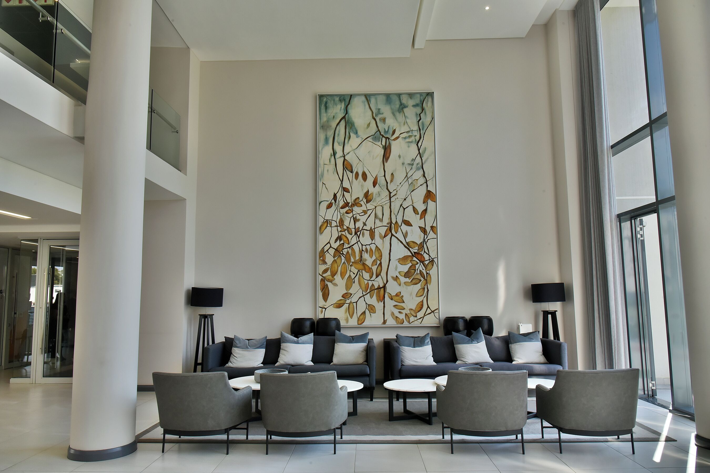 A modern lobby with a seating area, a large abstract painting, and a glass facade.