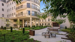 A courtyard with a multi-story building, outdoor seating, and greenery. - Native Apartments Smoleńsk 33 (Kraków)