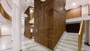 A modern hotel lobby with a central staircase, wooden paneling, and a sign labeled 'A'. - Native Apartments Smoleńsk 33 (Kraków)
