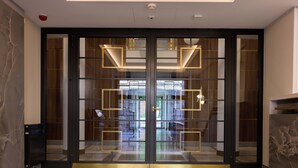 A modern entrance with glass doors and geometric lighting. - Native Apartments Smoleńsk 33 (Kraków)