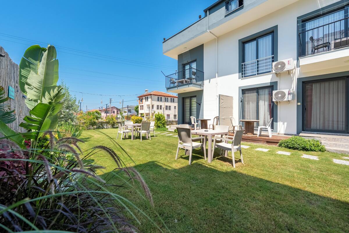 Un appartement moderne doté d’un balcon, d’un espace extérieur aménagé pour s’asseoir et d’une pelouse bien entretenue.