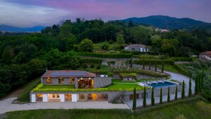A modern villa with a swimming pool, surrounded by lush greenery and a hilly landscape. - Villa Krisztina 10 Emma Villas (Bagnone)