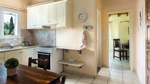 A kitchen with white cabinets, a stove, and a dining area with a wooden table and chairs.