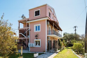 A multi-story building with balconies, a staircase, and a garden pathway.
