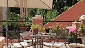 A round table with chairs, a hanging macrame light fixture, and potted plants.