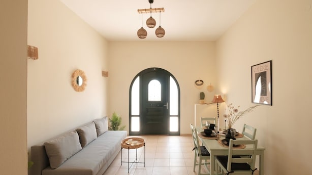 A modern living room with a sofa, dining table, chairs, and a staircase leading to an upper floor.