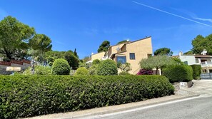 A residential area with a two-story house, a well-maintained hedge, and a clear sky. - CASA OSLO (Estartit)
