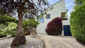 A building with a stone wall, a gravel path, and a large tree.