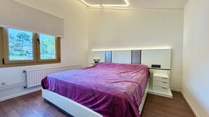 A bedroom with a bed, a window, a radiator, and a bedside table. - CASA OSLO (Estartit)