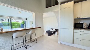 Eine moderne Küche mit eingebauter Mikrowelle, Barhocker und Blick durch ein Fenster.