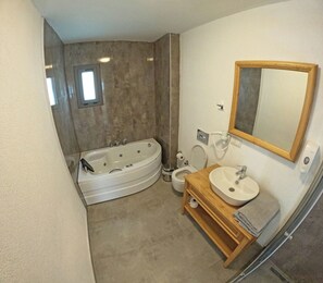 A modern bathroom with a freestanding bathtub, a toilet, and a sink with a mirror above. - Eski Kapı Datça  (Datça)