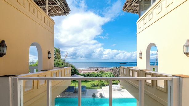 A balcony with a view of a swimming pool and beach. - Amani Beachfront Villa by YourHost (Watamu)