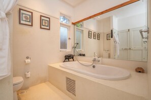 Een badkamer met een bad, toilet en douche.