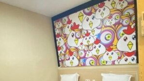 Une chambre d’hôtel avec deux lits simples, une fresque murale aux couleurs vives et un plancher en bois.