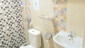 Une salle de bain avec une paroi de douche carrelée, des toilettes, un lavabo et un porte-serviettes.