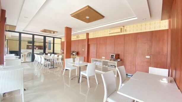 Une salle de conférence moderne, dotée de tables et de chaises blanches, d’une grande fenêtre et d’un mur décoratif en bois.
