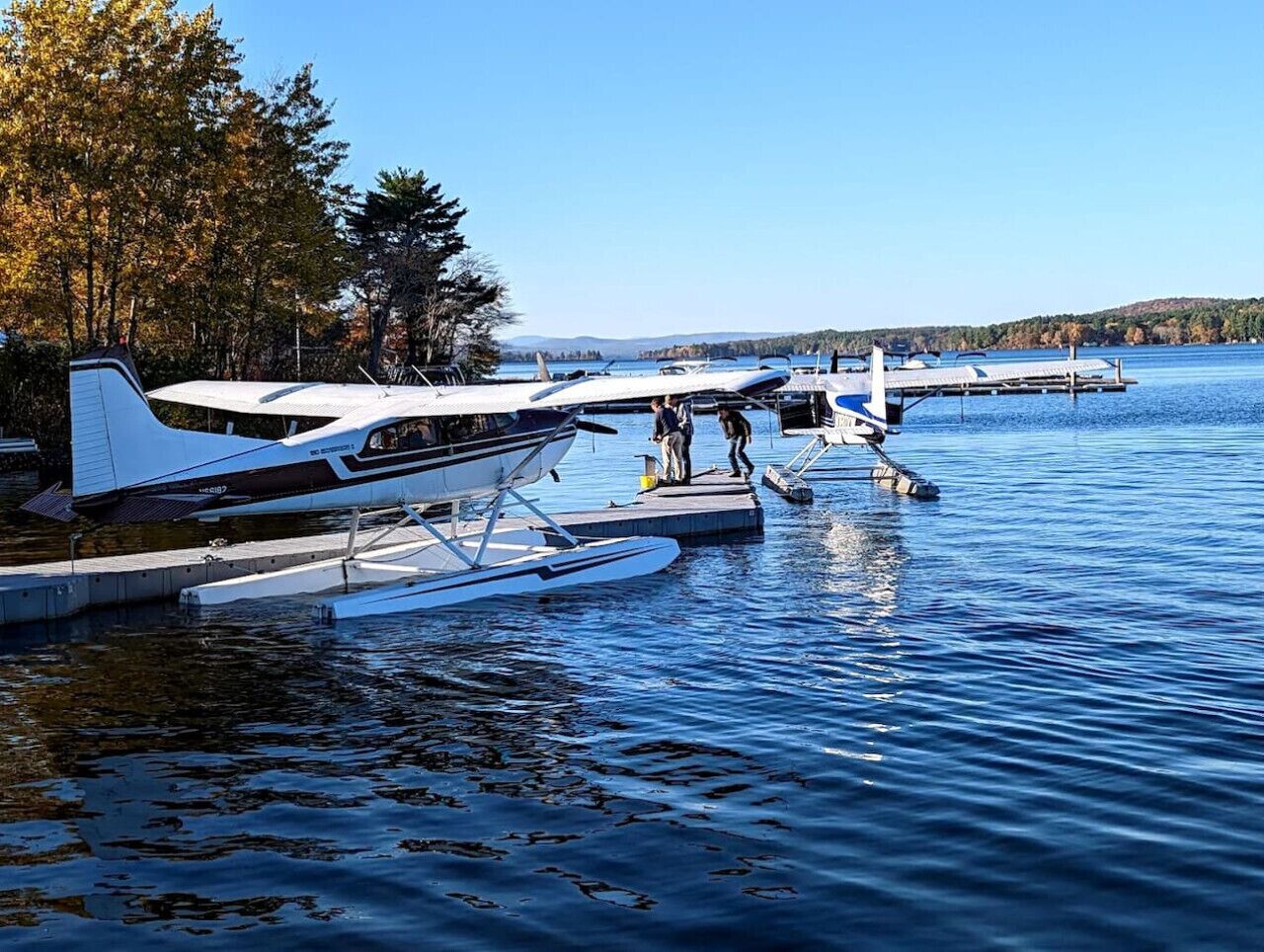 A lake with two seaplanes docked on floating platforms.