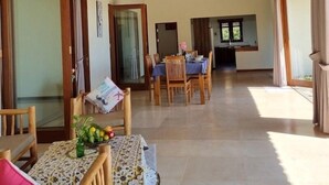 A spacious living area with high ceilings, wooden beams, and a dining area with a table and chairs. - Ponjok Batu Residence (Tejakula)