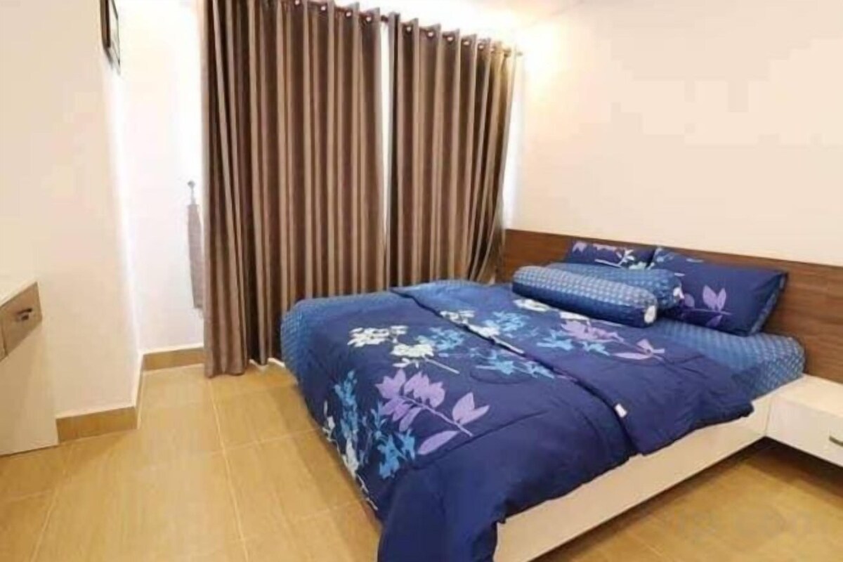 Un dormitorio con cama, cortinas y mesita de noche.