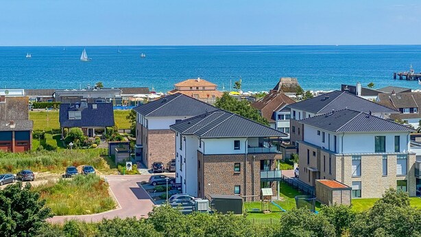 Una zona residencial costera con casas modernas, un puerto deportivo y vista despejada al mar.