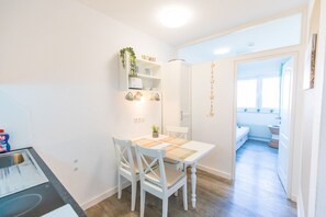 A compact kitchen with white cabinetry, a dining table with chairs, and a small countertop. - Wind im Haar, Sonne im Gesicht, Meer im Blick (Dahme)