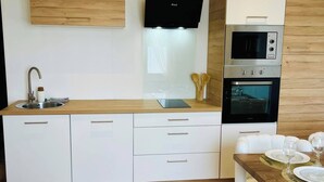 Una cocina moderna con horno empotrado, microondas y campana extractora negra.