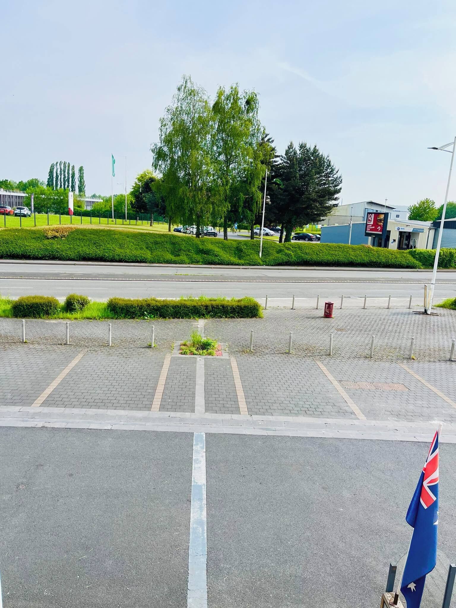 A parking lot with a flag, paved walkways, and a building in the background.