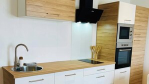 Cocina moderna con encimera de madera, armarios blancos, horno integrado y campana extractora negra.