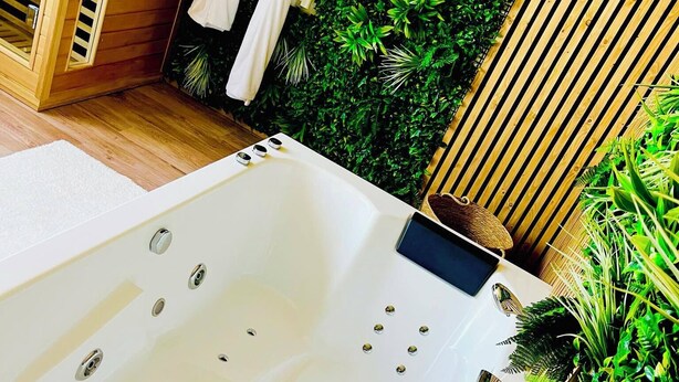 Un baño moderno con una bañera grande, paneles de madera y exuberantes plantas verdes.
