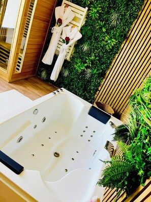Ein modernes Badezimmer mit einer großen Badewanne, Holzverkleidung und üppigem Grünwerk.