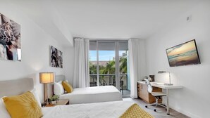 A modern hotel room with a bed, desk, and large windows. - Stylish Studio | Pool Amenities | Steps to Beach (Hallandale Beach)