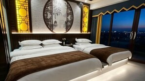 A hotel room with two beds, a large window with a city view, and decorative wall panels.