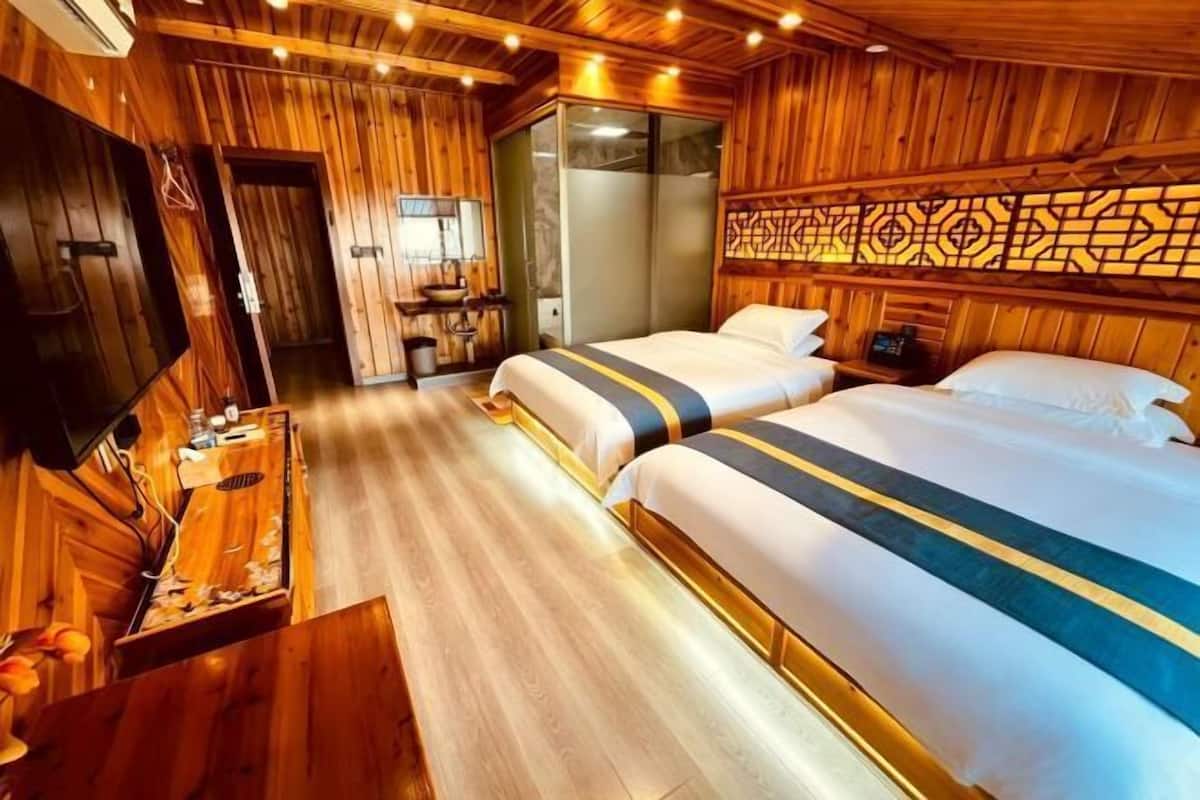 Ein hotelzimmer im Holzdesign mit zwei Betten, einem Fernseher, einem Schreibtisch und einem Badezimmer.