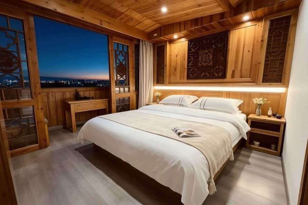 Ein Schlafzimmer mit einem großen Bett, Holzwänden und Blick auf die Stadt sowie einem Nachthimmel.