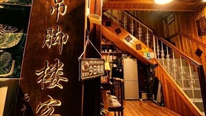 A wooden interior with a staircase, a sign with Japanese characters, and a refrigerator.