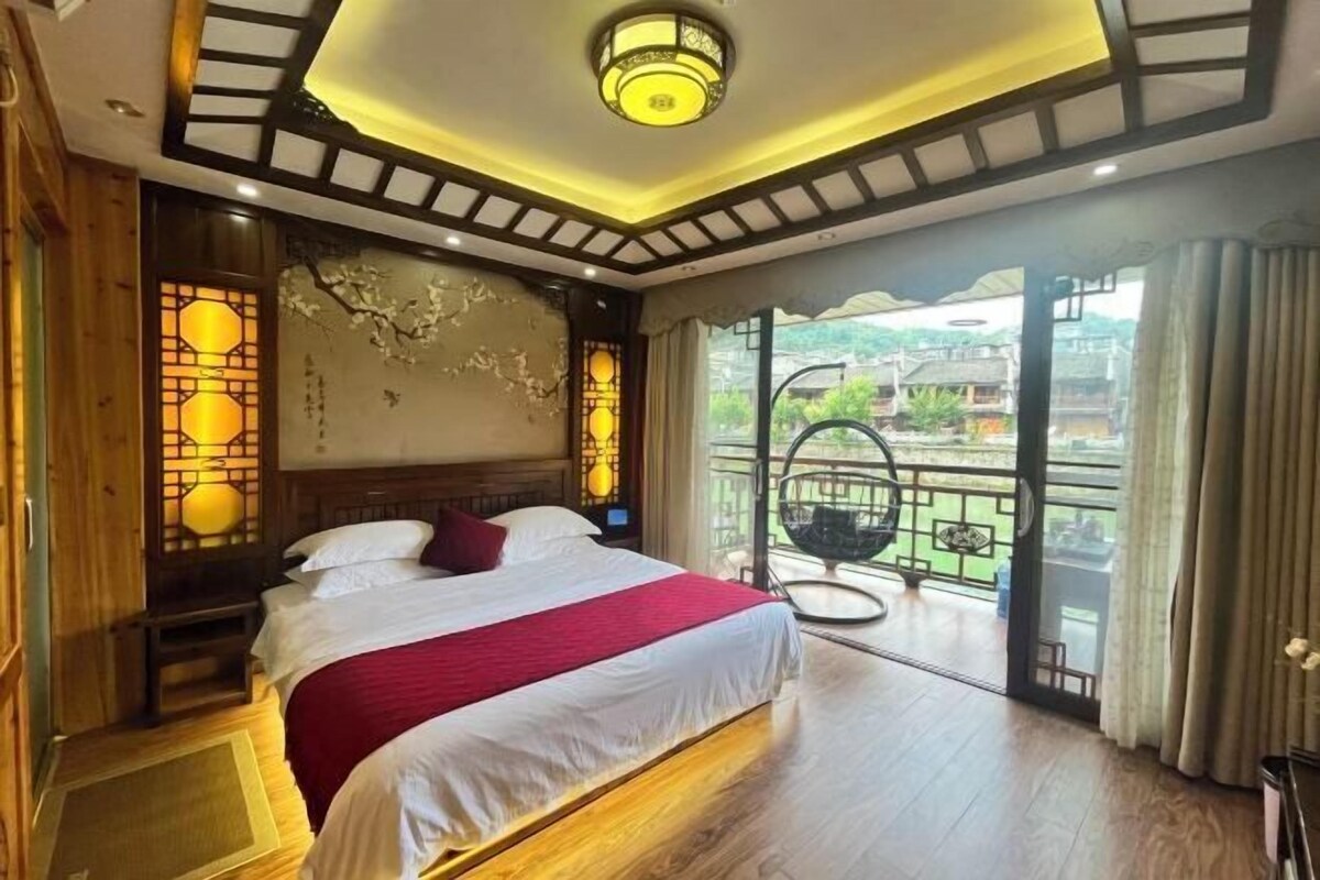A hotel room with a large bed, wooden accents, a balcony with a view, and traditional decor.