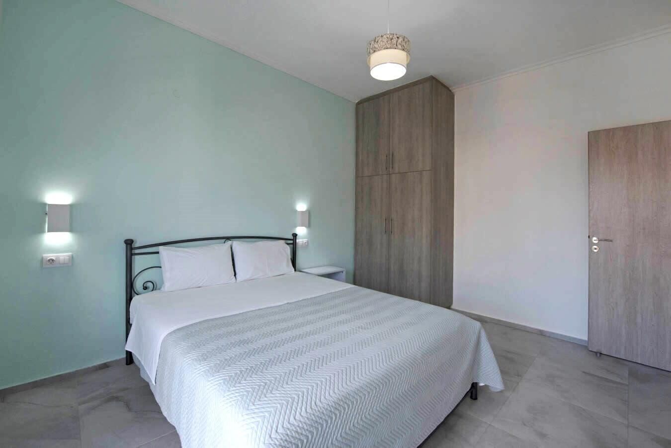 A bedroom with a bed, bedside tables, a wardrobe, and a ceiling light fixture.