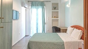 A bedroom with a bed, a desk, and a chair. There is a wardrobe on the left and a shelf with decorative items on the wall. - Sweet apartment in Athens A3 (Athina)