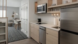 A modern kitchen with stainless steel appliances, wooden cabinets, and a built-in dishwasher. - TownePlace Suites by Marriott Eugene (Eugene)