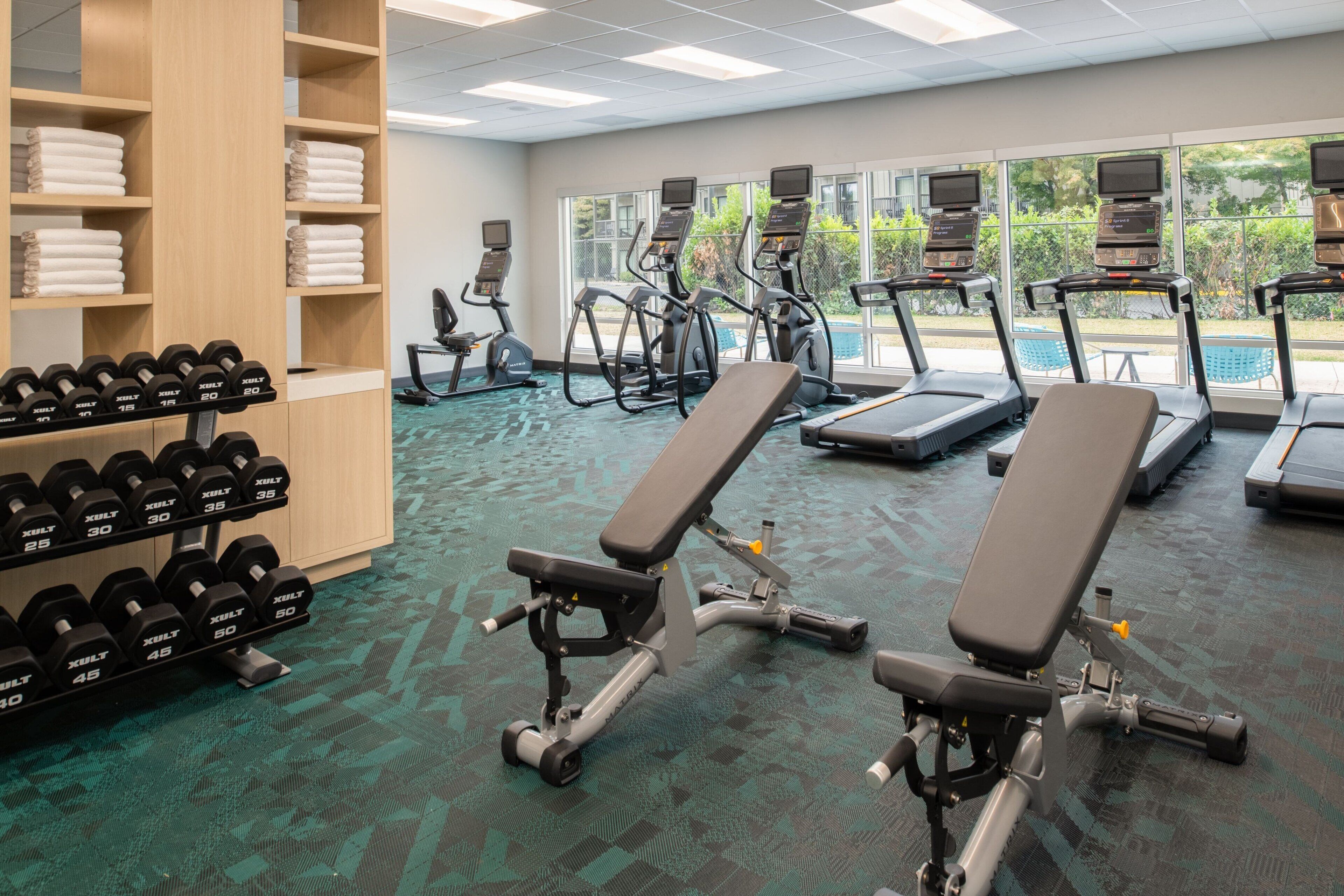 A gym with treadmills, elliptical machines, and weight benches.