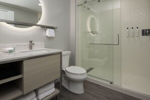 A modern bathroom with a toilet, sink, and shower. - TownePlace Suites by Marriott Eugene (Eugene)