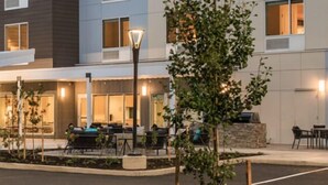 A hotel exterior with outdoor seating, a street lamp, and a tree. - TownePlace Suites by Marriott Eugene (Eugene)
