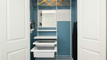 A walk-in closet with white shelves, a mirror, and wooden hangers.