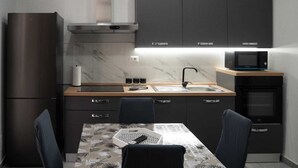 A modern kitchen with a refrigerator, microwave, oven, and a dining table with chairs. - GIORGIA'S HOUSE - VACATION HOME (Catania)