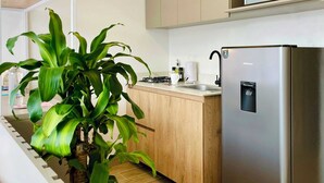 Une cuisine moderne équipée d’un réfrigérateur en acier inoxydable, de meubles de rangement en bois, d’un four à micro-ondes et d’un évier.