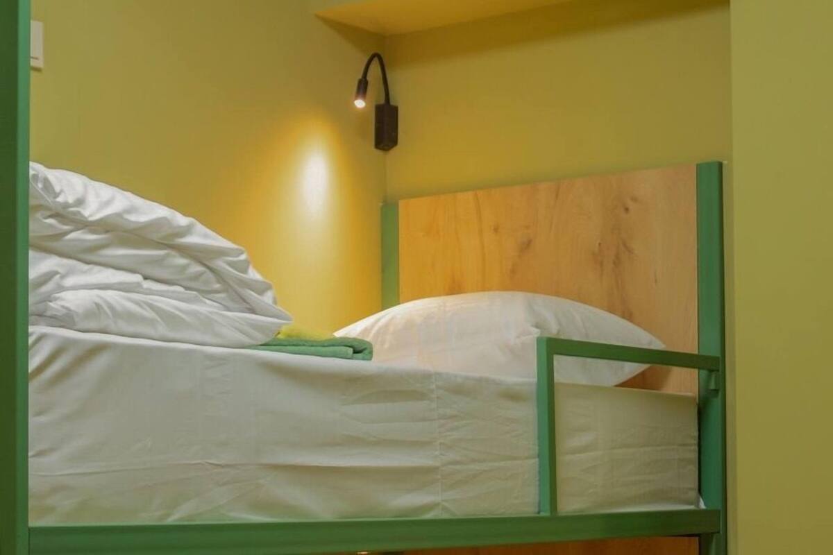 A bunk bed with a wooden headboard and a single bedside lamp.