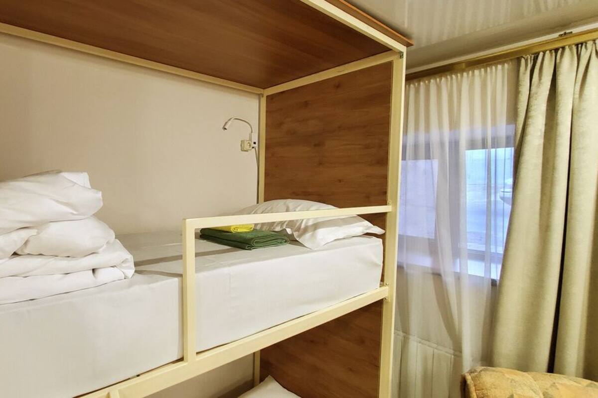 A bunk bed with white bedding and a green towel.