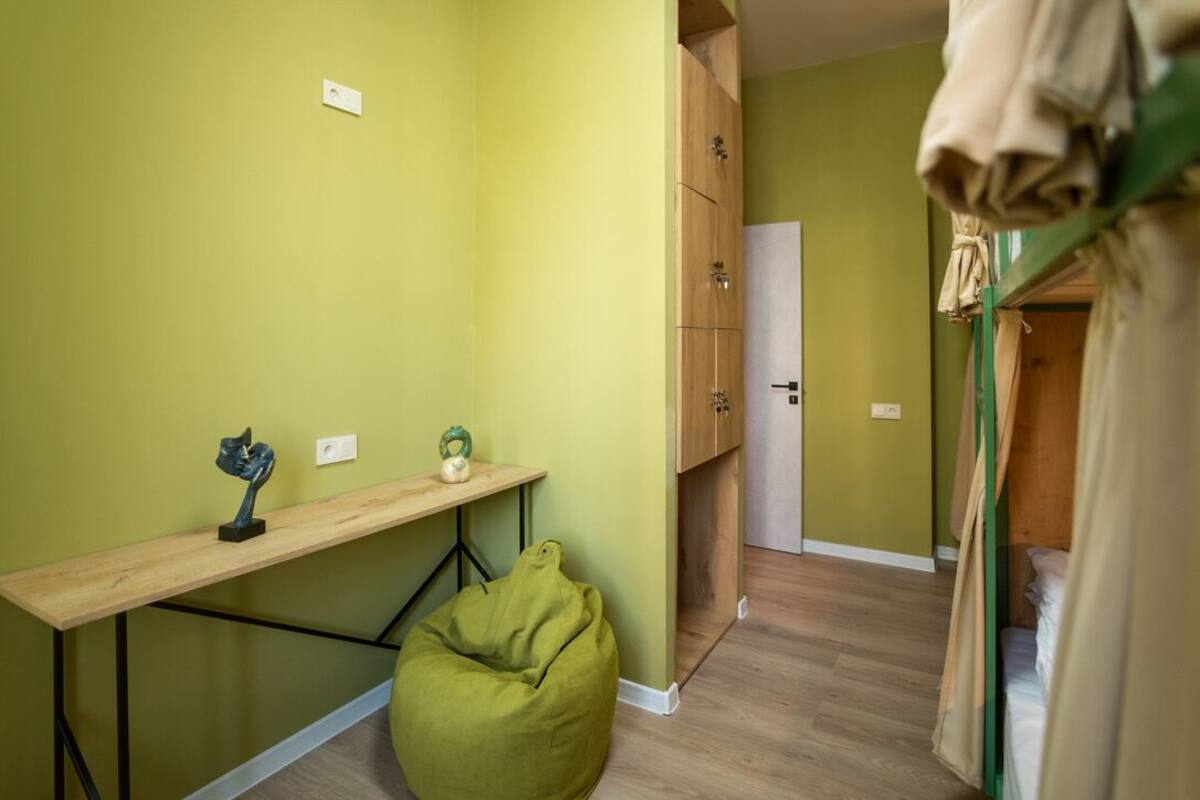 A room with a wooden desk, a bean bag chair, a wardrobe, and a bunk bed.