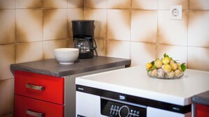 Une cuisine équipée d’une machine à café, d’un bol et d’une assiette contenant des citrons, le tout posé sur le comptoir.