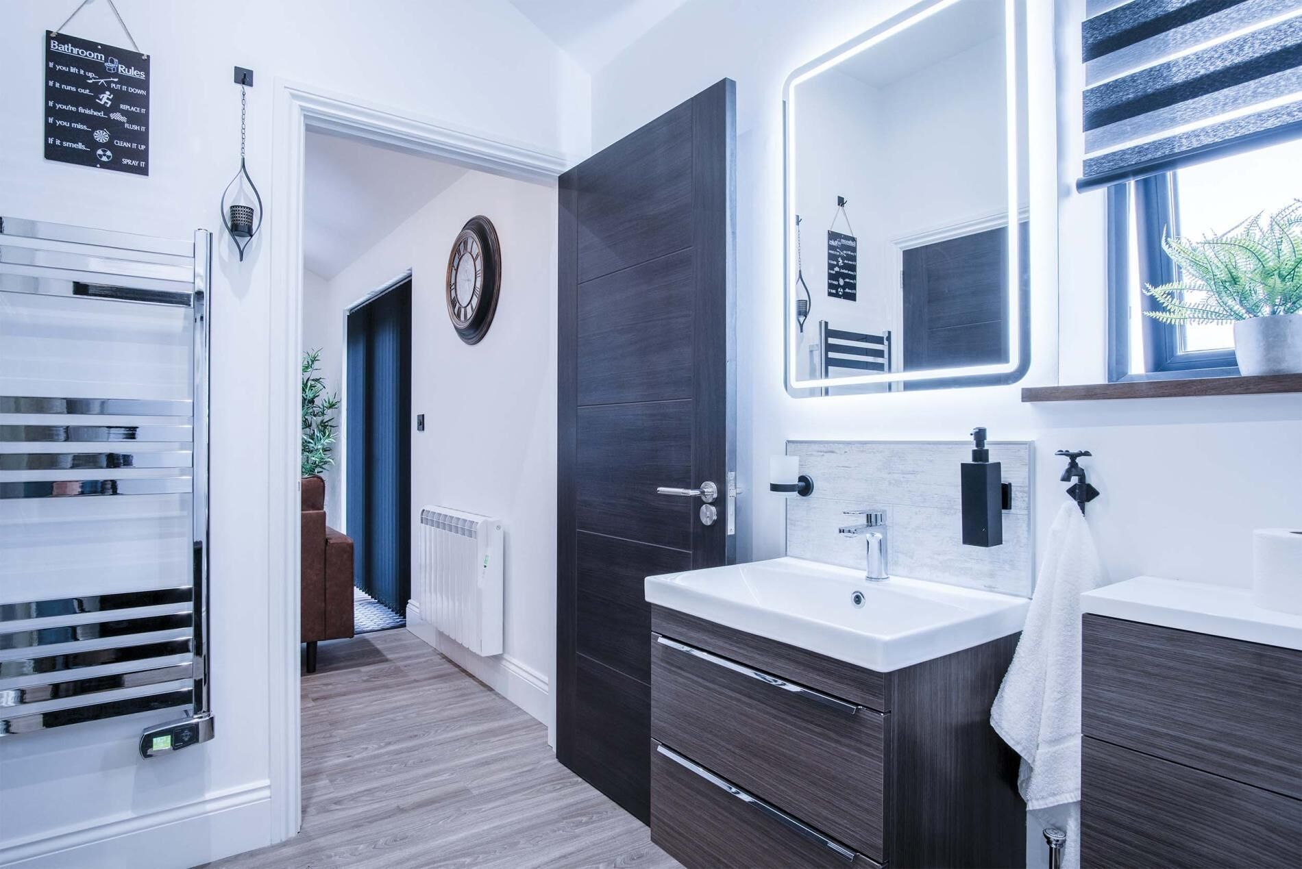 A modern bathroom with a large mirror, a sink, and a towel hanging on the wall.